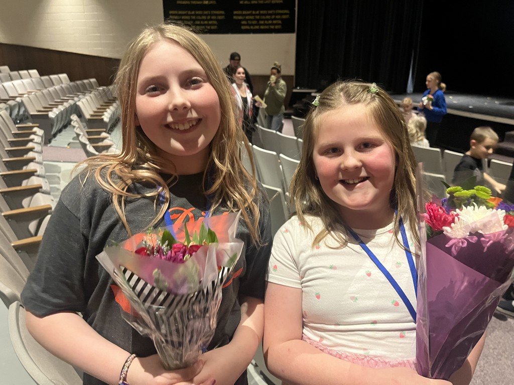 two girls  each holding a bouquet of flowers and smiling 