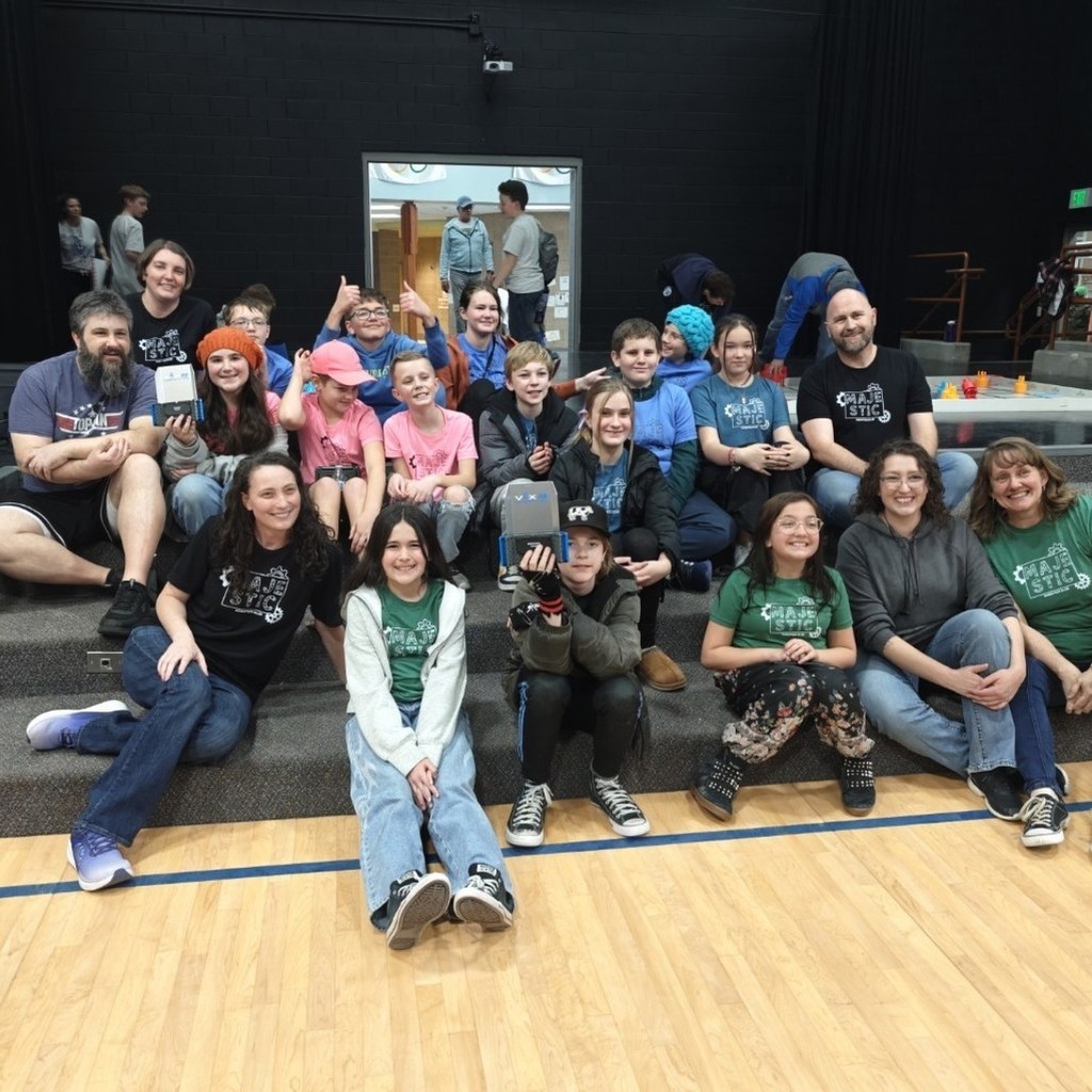 Students from robotics team and their coaches sitting in stage steps. 