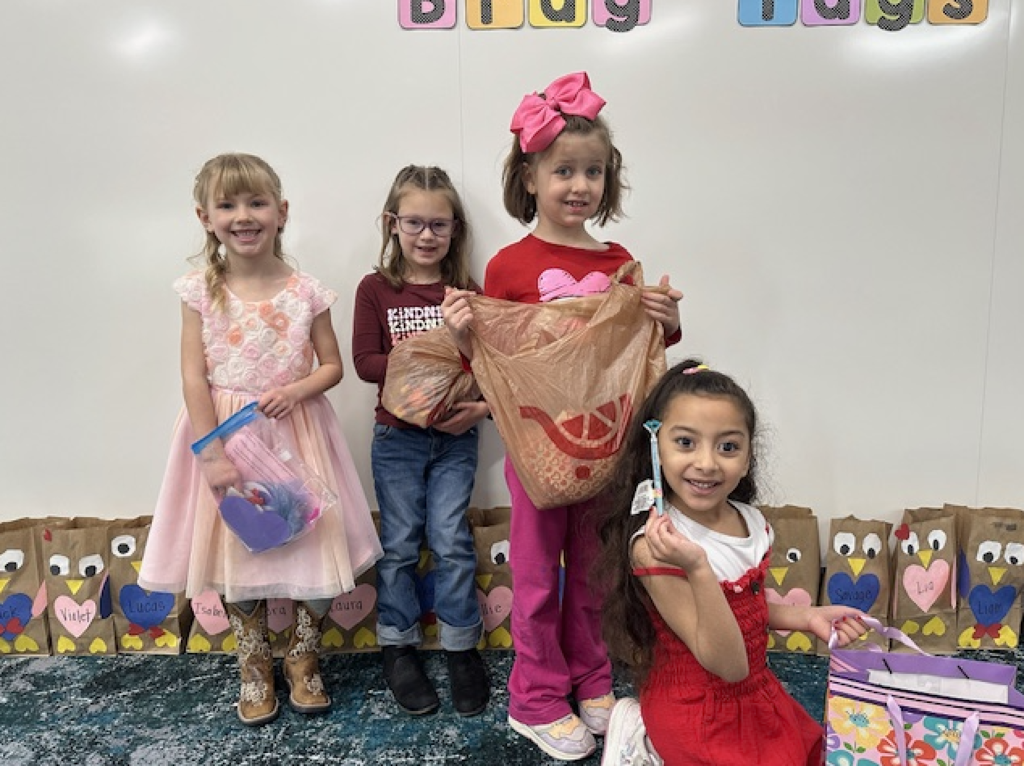 students smiling and holding a valentine's from classmates