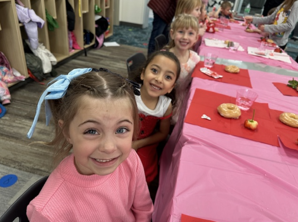 students smiling and eating a valentine's snack