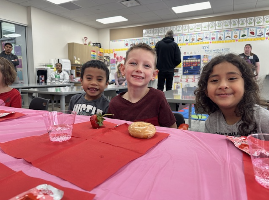 students smiling and eating a valentine's snack