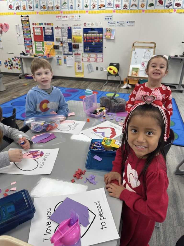 students smiling and working on a valentine's art project