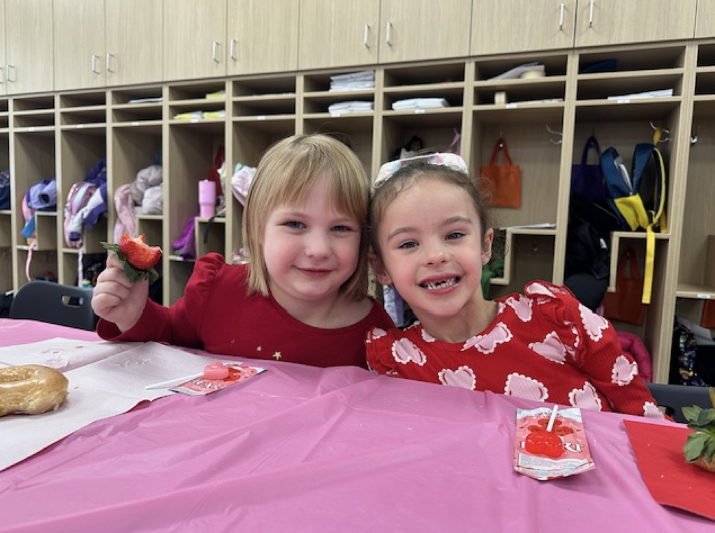two students smiling and eating a valentine's snack