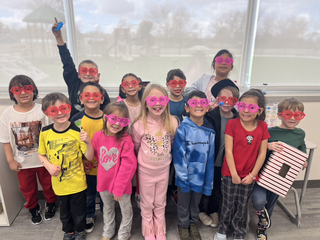 1st grade students standing as a group with heart glasses on