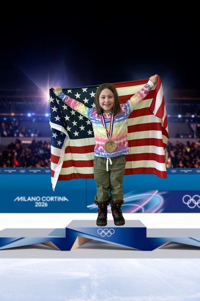 first grade student standing on an olympic podium wearing a gold medal and holding the USA Flag