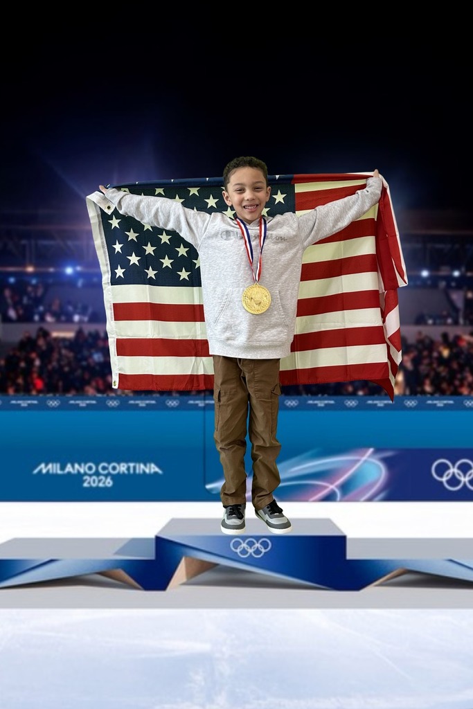 first grade student standing on an olympic podium wearing a gold medal and holding the USA Flag