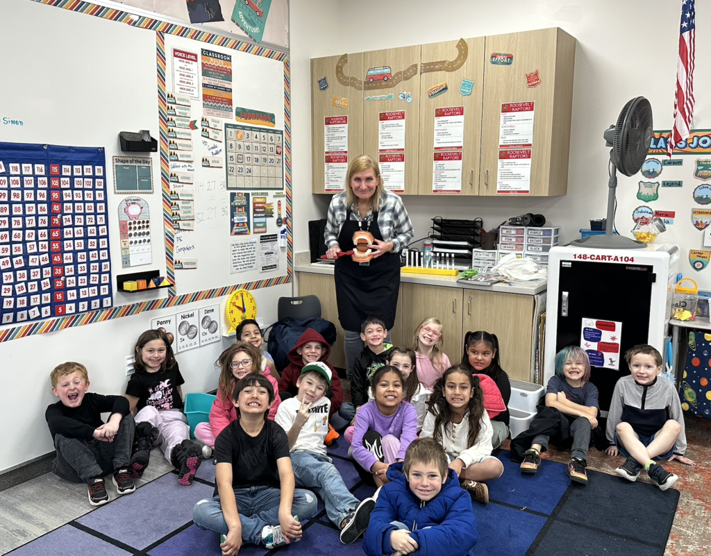 first grade class posing with the school nurse as they learn about correctly brushing their teeth