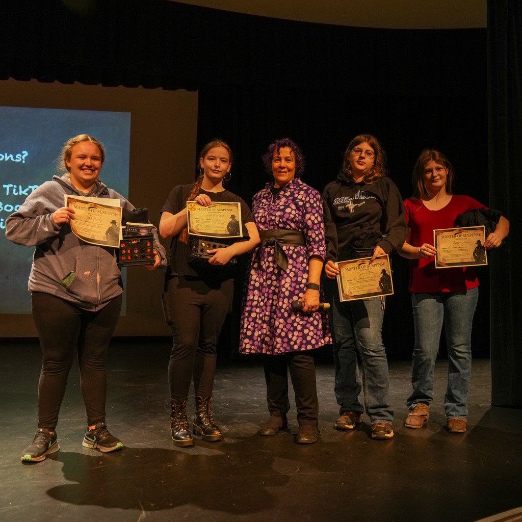 Students listening and receiving signed book from author