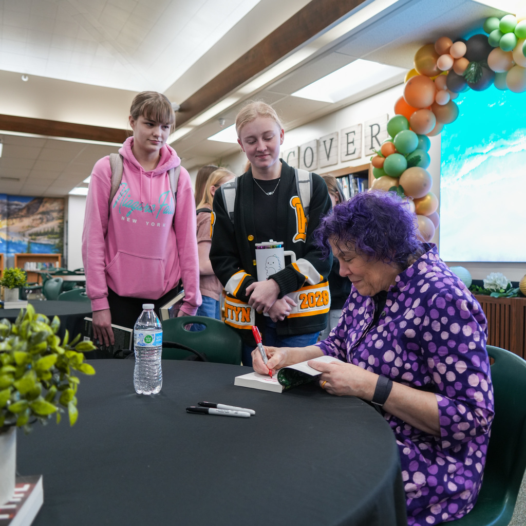 Students listening and receiving signed book from author