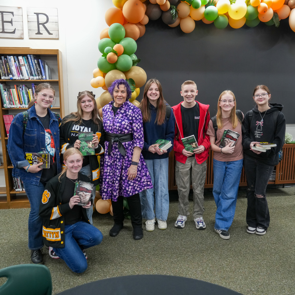 Students listening and receiving signed book from author