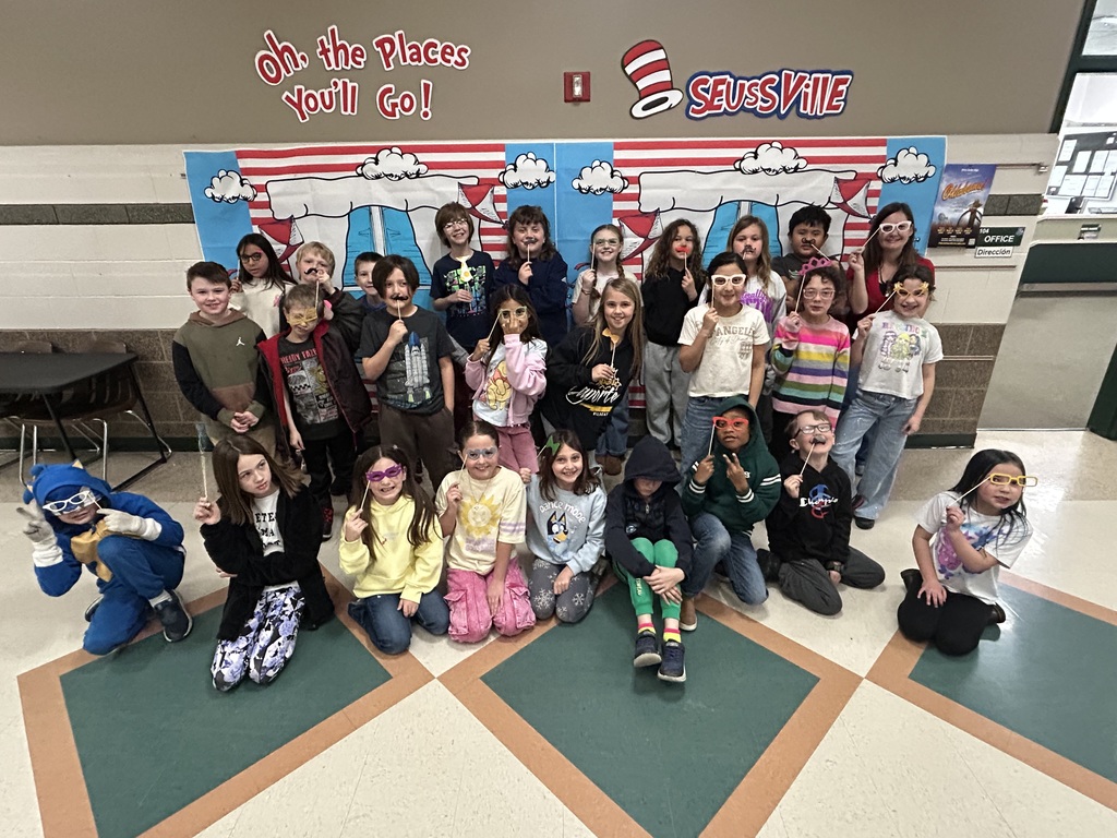 Mrs. Weston's class in front of a Dr. Seuss banner, holding props.