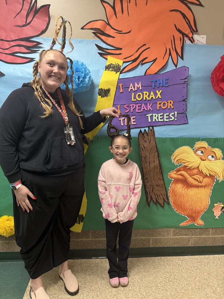 Miss Jenn and a student with crazy hair. Jenn has a tall pony tail and the girl has a braid in the shape of 67