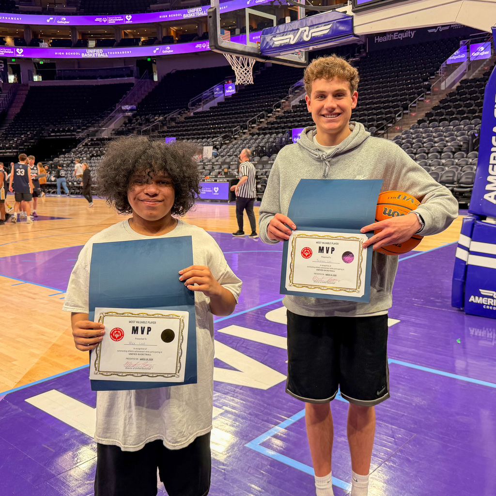 Two players holding up MVP awards on the edge of the court