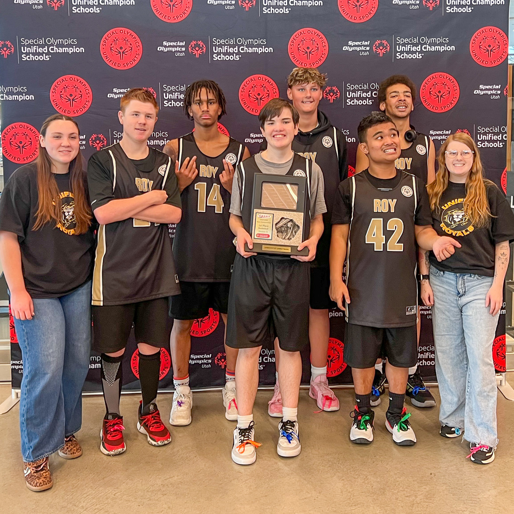 Team photo with a backdrop for the Unified Sports holding a trophy