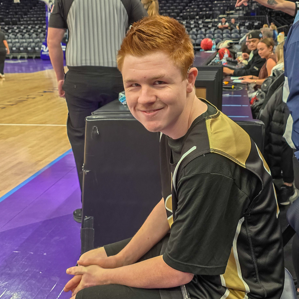 A basketball player sitting on the bench smiling