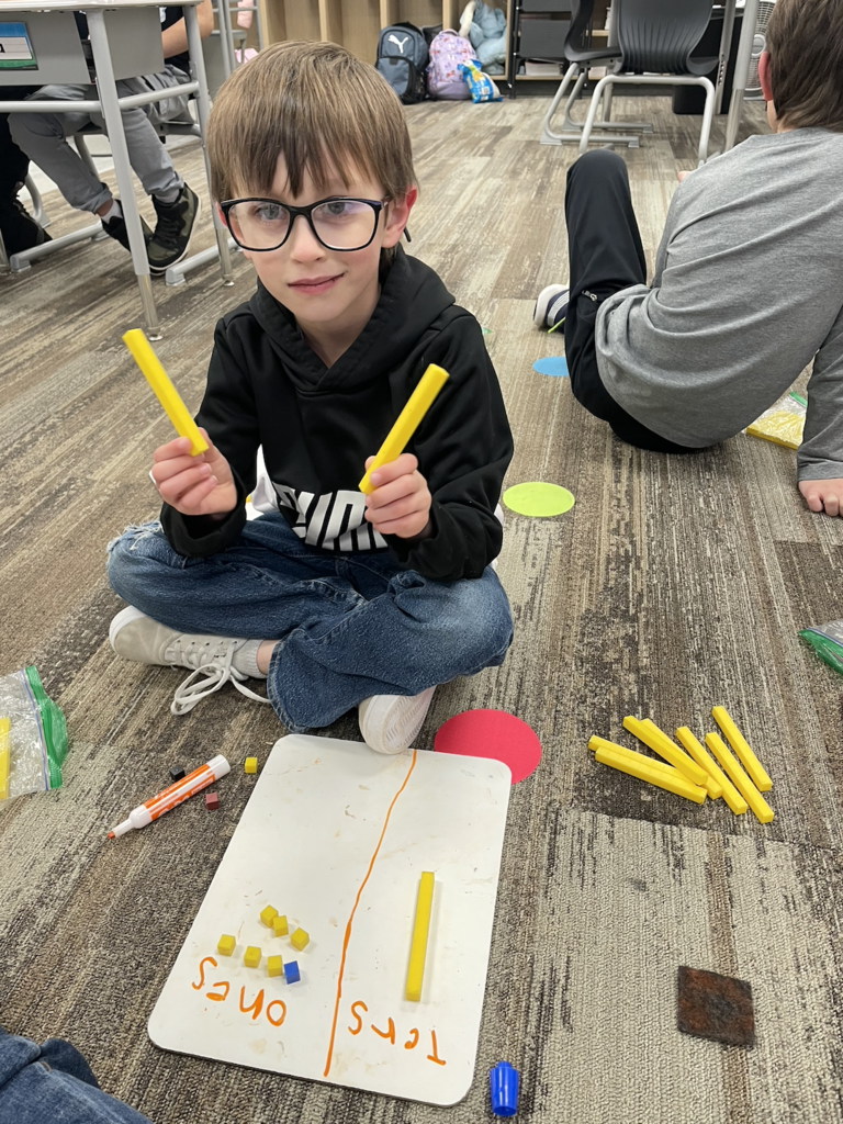 students smiling and using tens and ones sticks for math