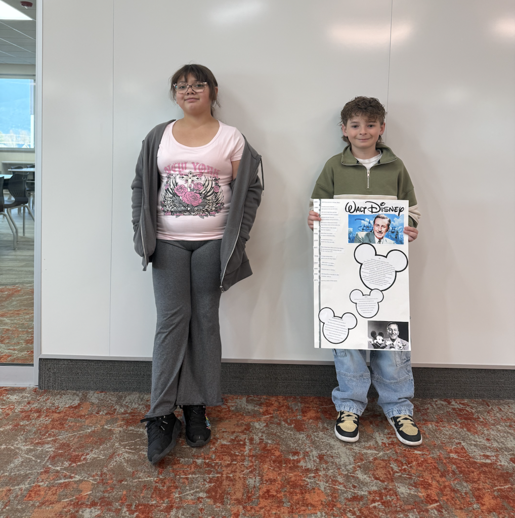 two students holding posters for the wax museum