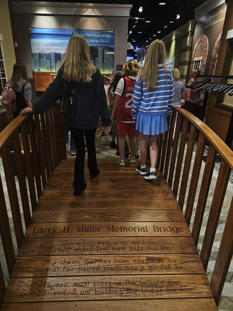 Students walking across the wooden Larry H. Miller Memorial Bridge, which features an inspiring poem about building a path for future generations.