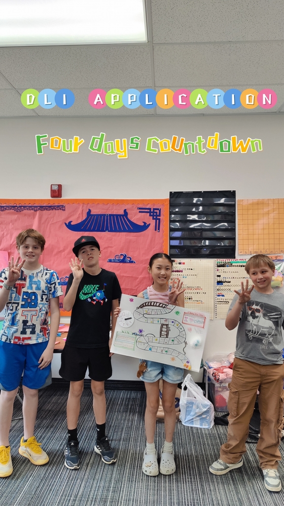 Four smiling students in a classroom hold up four fingers, standing in front of a bulletin board that says "DLI APPLICATION" and "Four days countdown." A girl holds a hand-drawn game