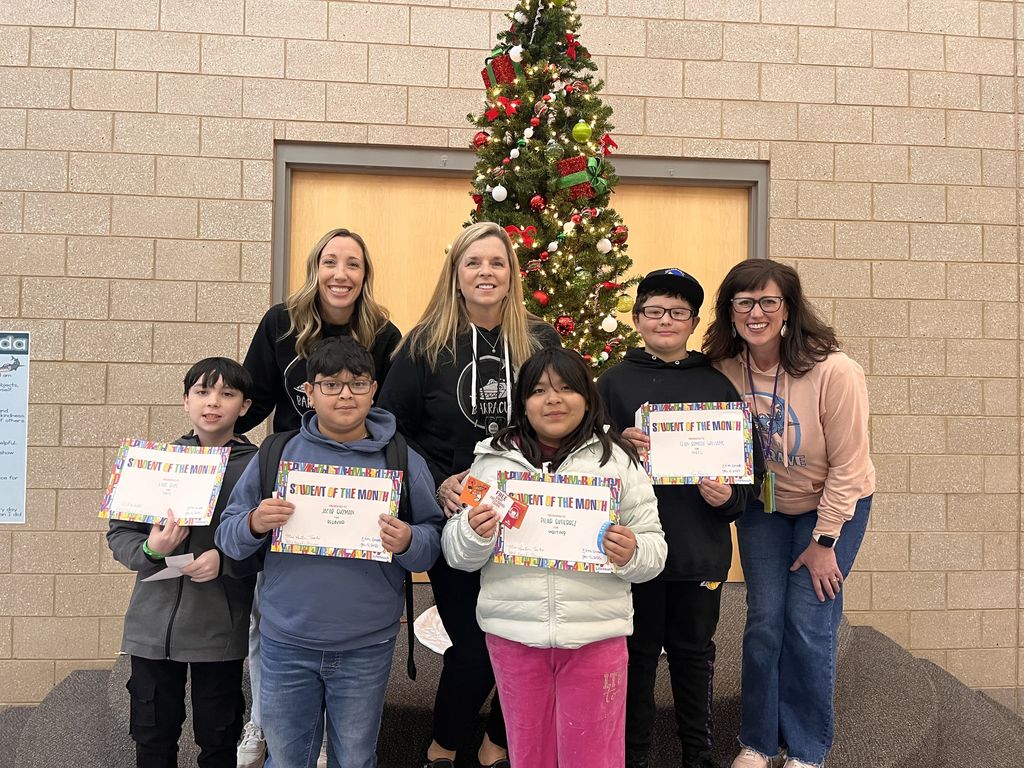 Photograph of student and citizen of the month award with teacher and students.