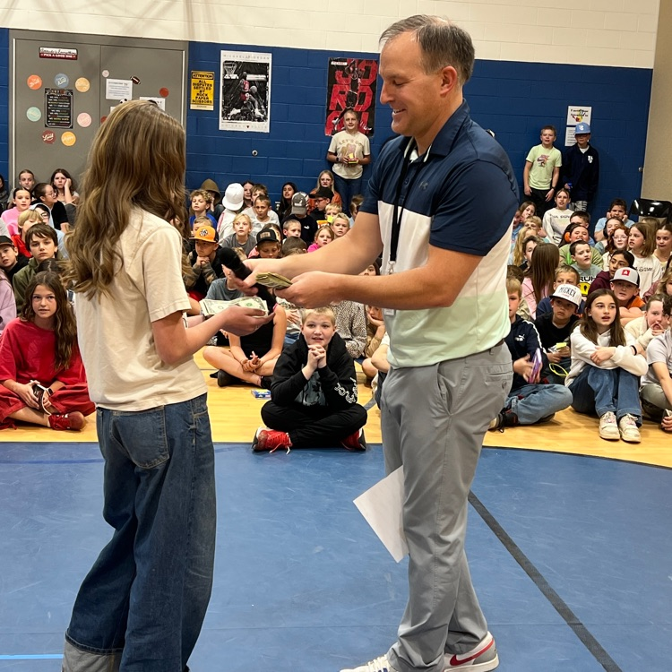 students receiving dollar bills from principal for participating in school-wide reading challenge. 