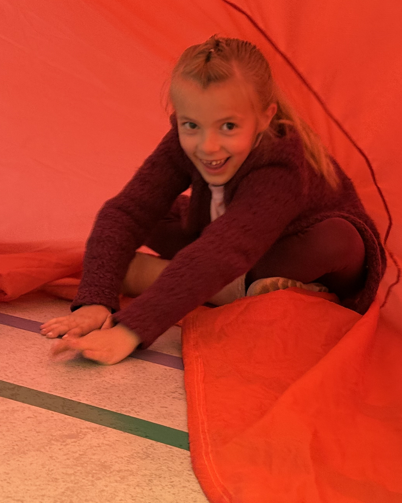 Student smiling while  exploriing a parachute activty during a PE lesson. 