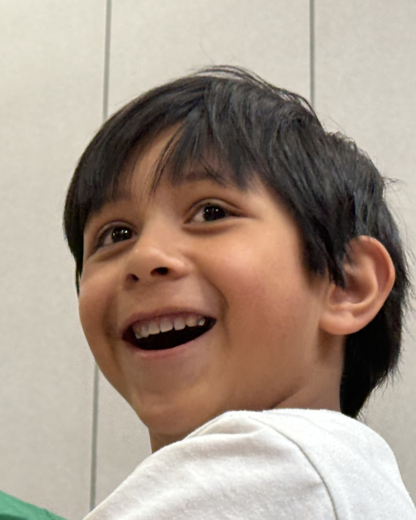 Student smiling while  exploriing a parachute activty during a PE lesson. 