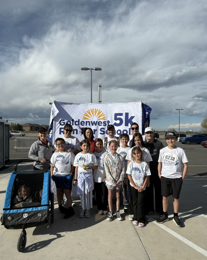 students and staff together as a group at the 5k fun run in front of the banner 