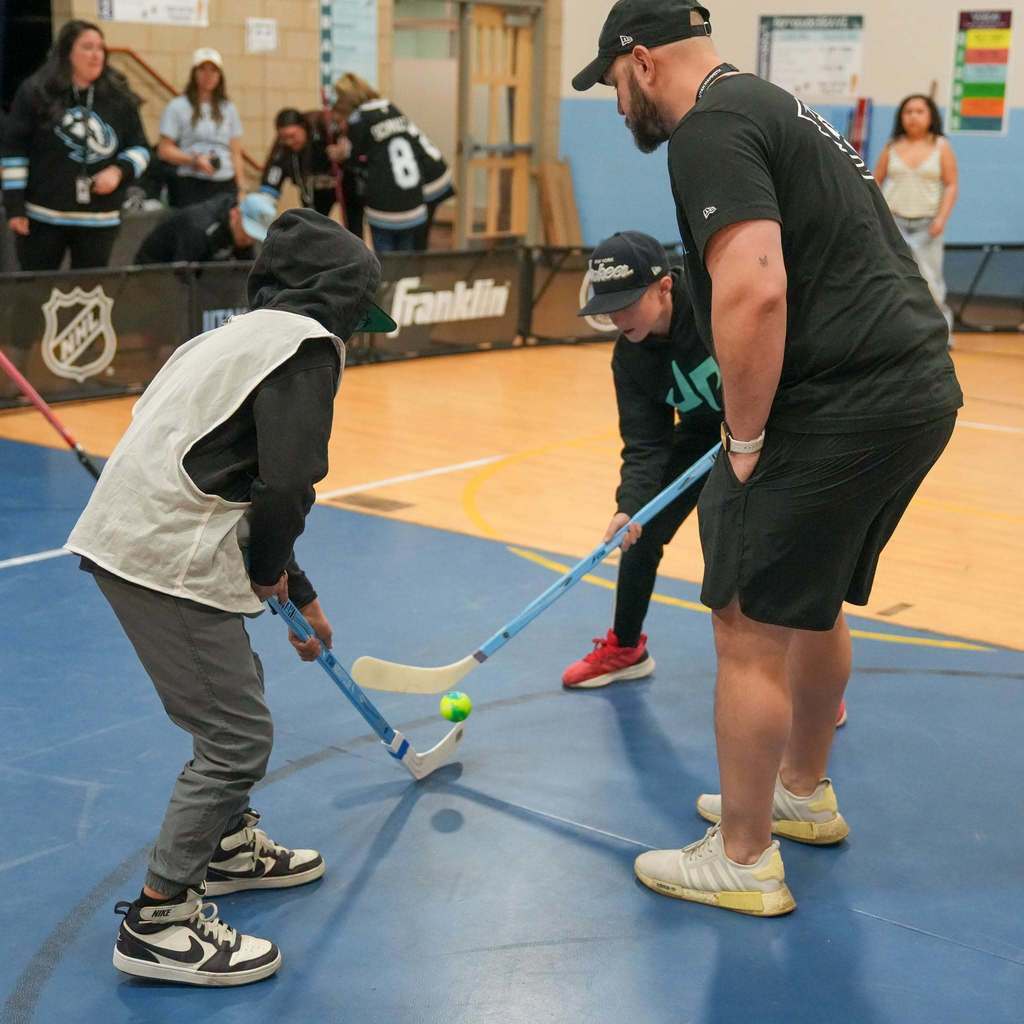 Students in the gym learning how to play street hockey from the Utah Mammoth.