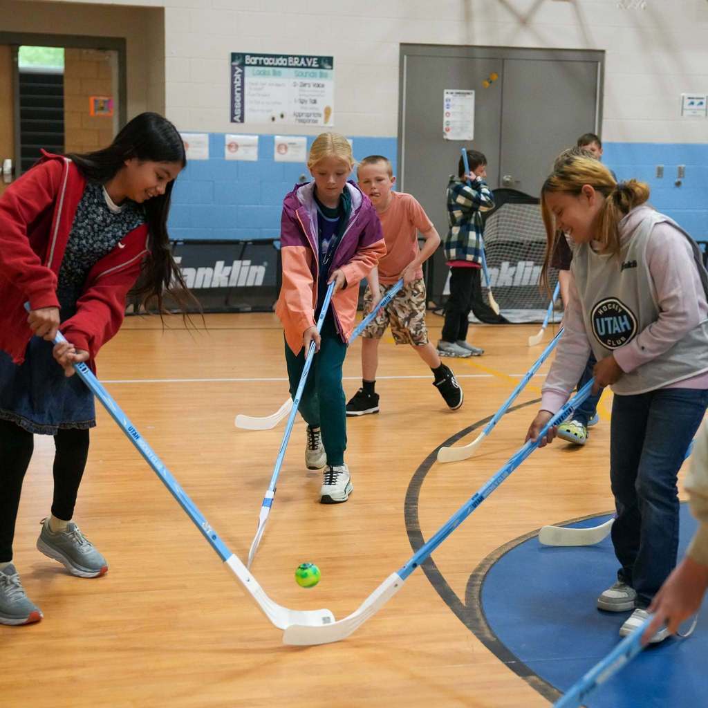 Students in the gym learning how to play street hockey from the Utah Mammoth.