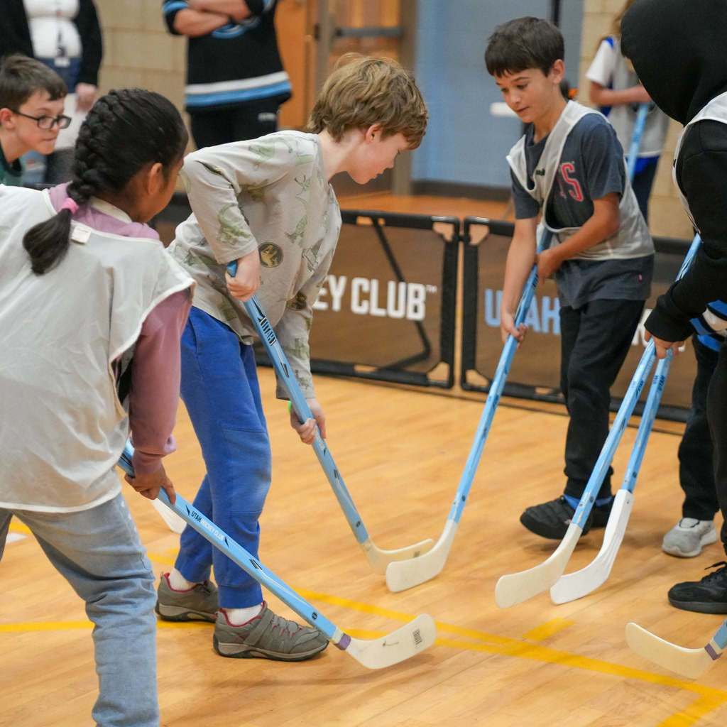 Students in the gym learning how to play street hockey from the Utah Mammoth.