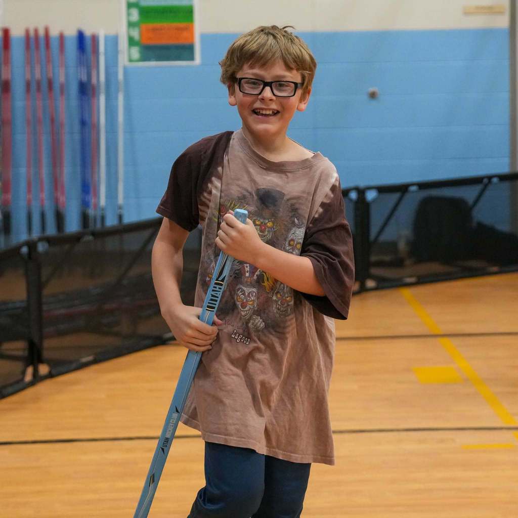Students in the gym learning how to play street hockey from the Utah Mammoth.