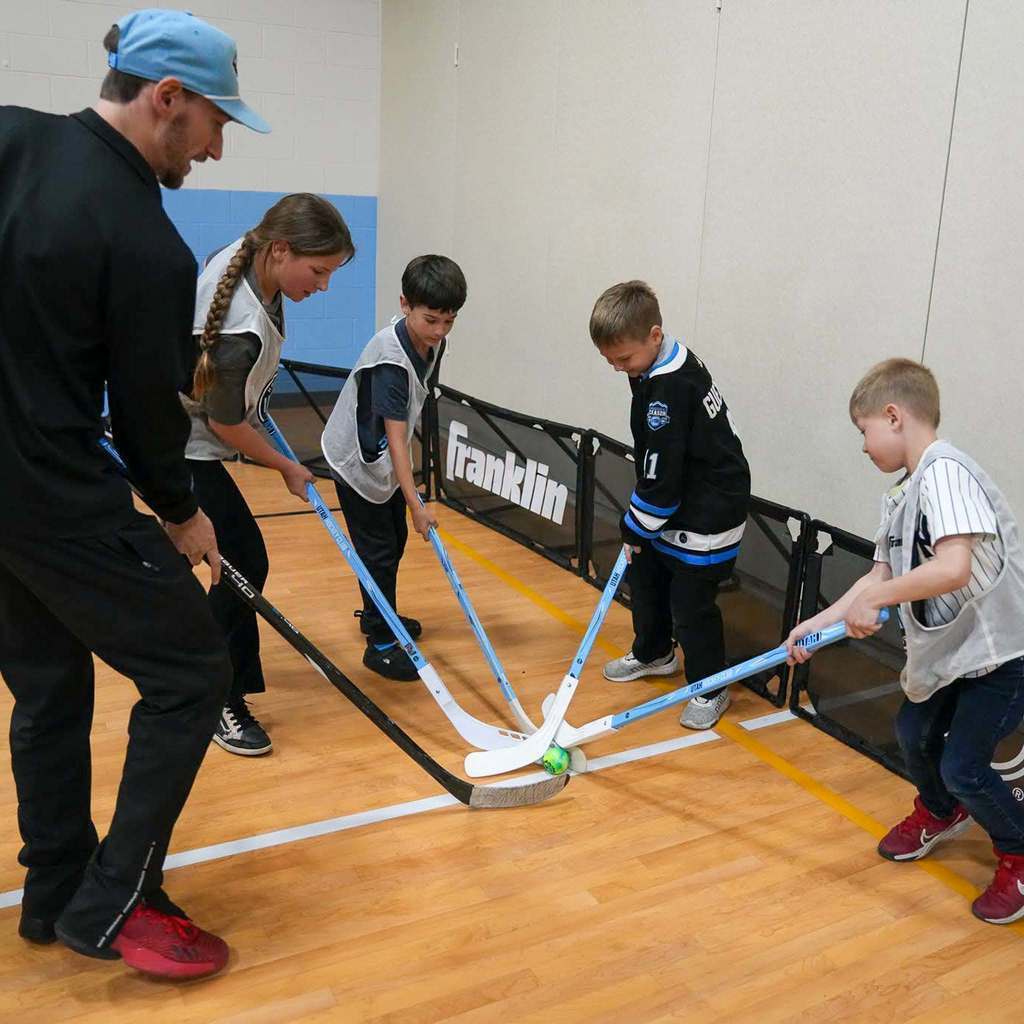 Students in the gym learning how to play street hockey from the Utah Mammoth.