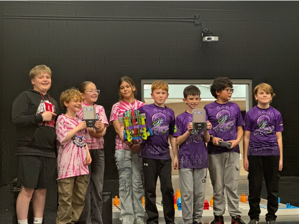 Two robotics teams posing with their robot and award at a robotics competition
