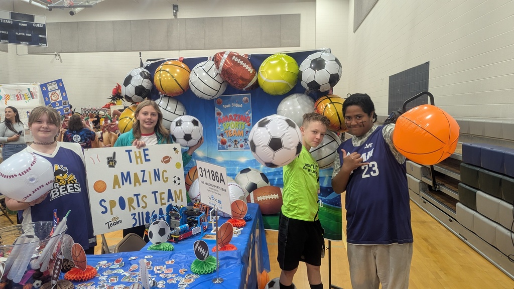 4 students posing at their booth a the state robotics competition