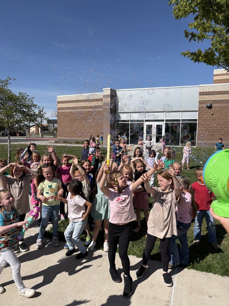 Kids playing with bubbles outside of a school.