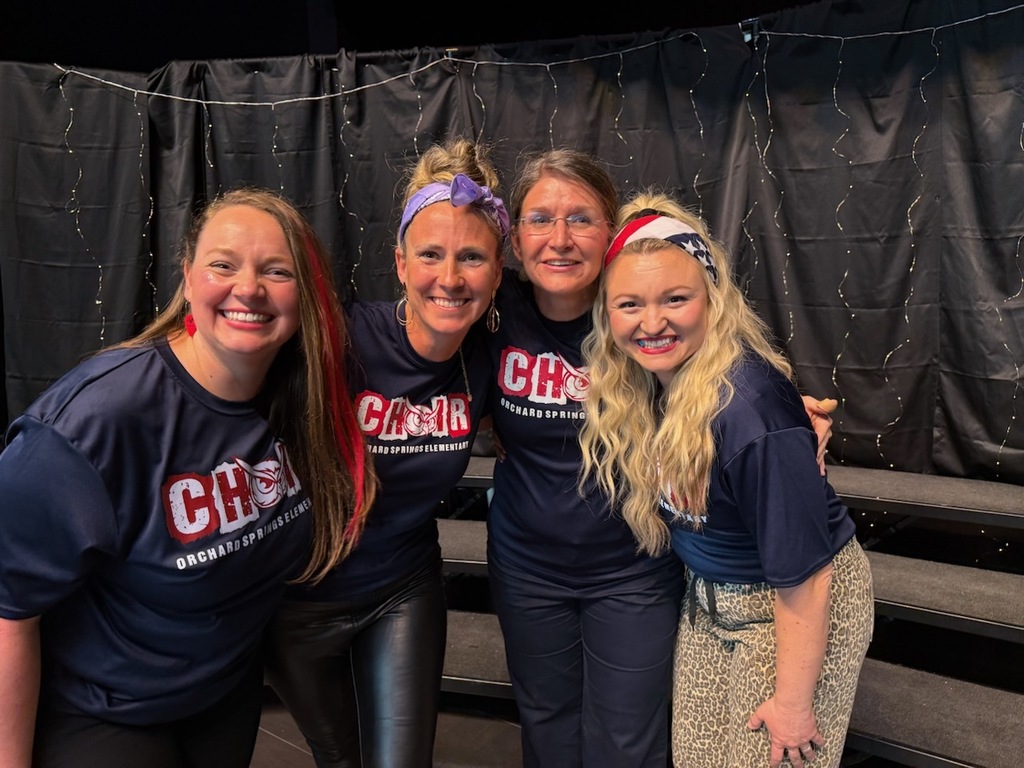 Group of 4 of the choir directors smiling in choir shirts! 
