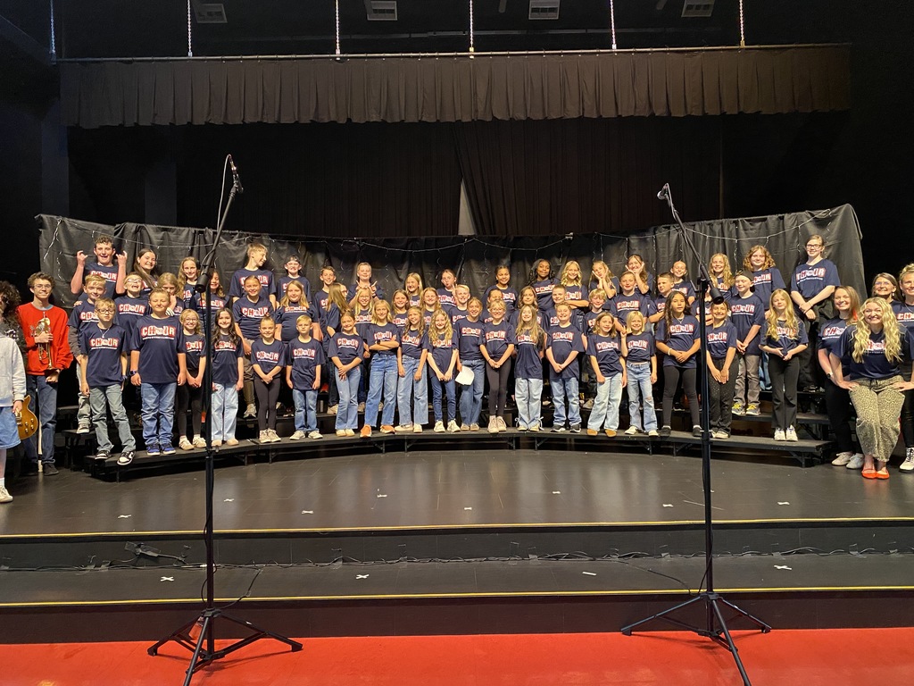 Entire group standing on stage in matching choir shirts. 