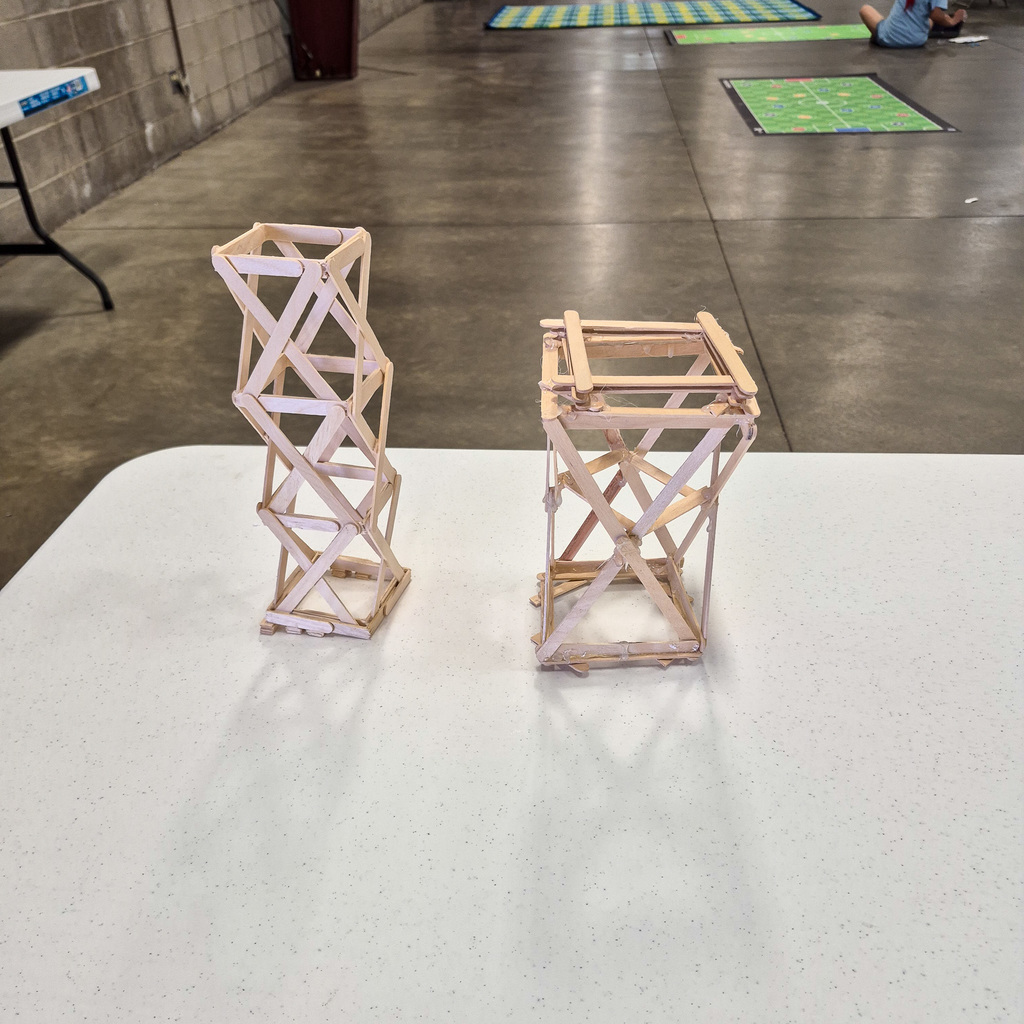 Close-up of two intricate towers constructed out of wooden craft sticks and glue, showcasing student engineering and structural design.