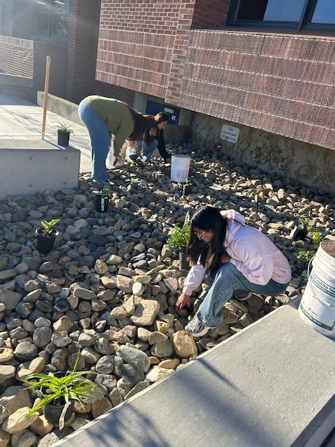 Students planting in the front flower beds of Bonneville.