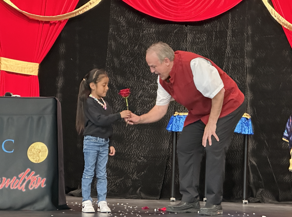student on stage receiving a rose from the magician