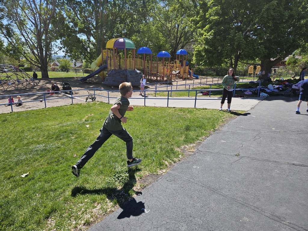 A young boy in a green shirt is captured mid-stride, running past a colorful playground structure.
