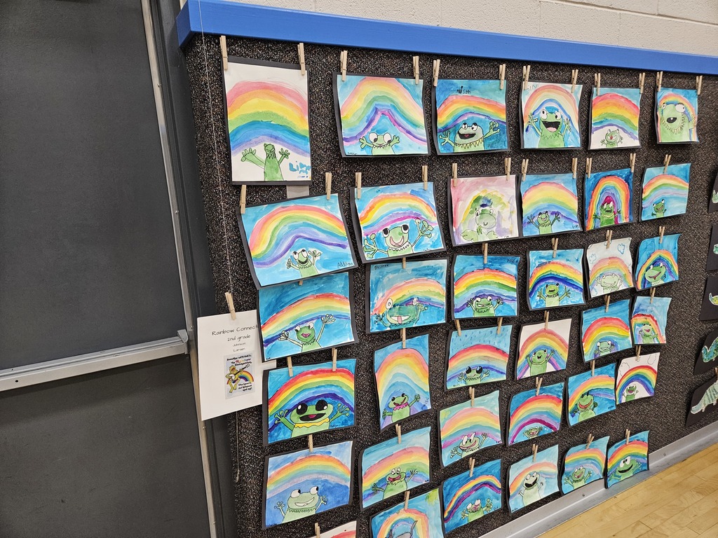 A wall display of student artwork featuring Kermit the Frog under vibrant watercolor rainbows.