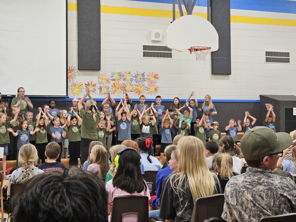 Another section of the choir performing with high energy, led by a teacher with her back to the camera.