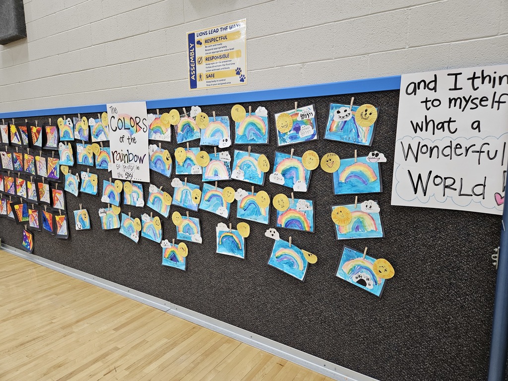  A bulletin board with rainbow paintings and suns next to a sign that reads, "And I think to myself, what a Wonderful World!"