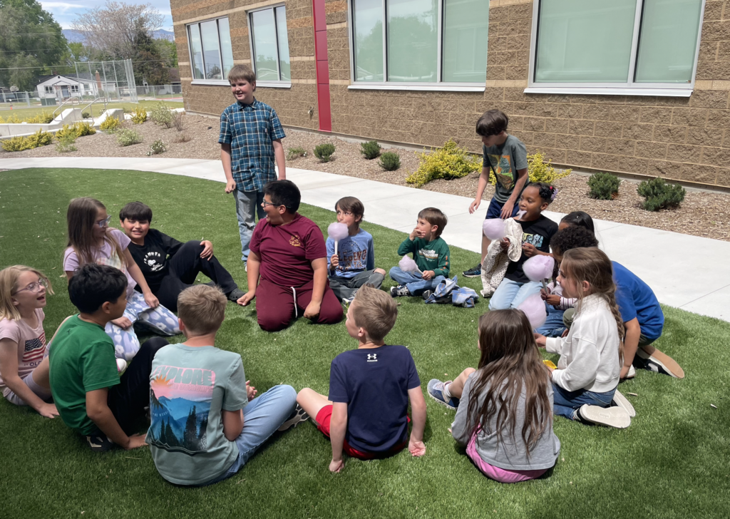 students sitting on the lawn chatting and eating cotton candy