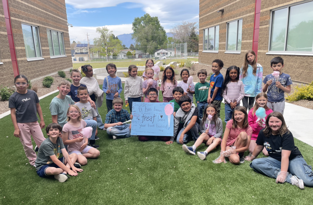 4th grade and 1st grade reading buddies together as a group holding a sign saying "its been a treat being your book buddy"