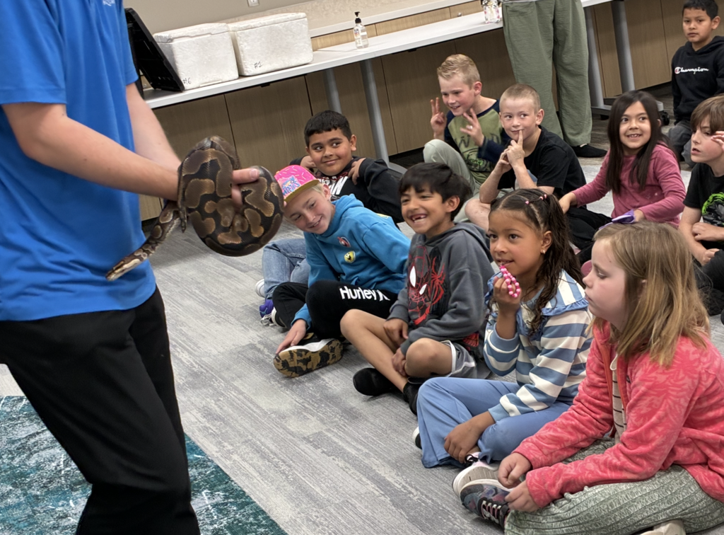2nd grade students being shown a snake from the rainforest