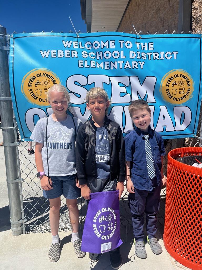three students smiling with the stem olympiad sign 