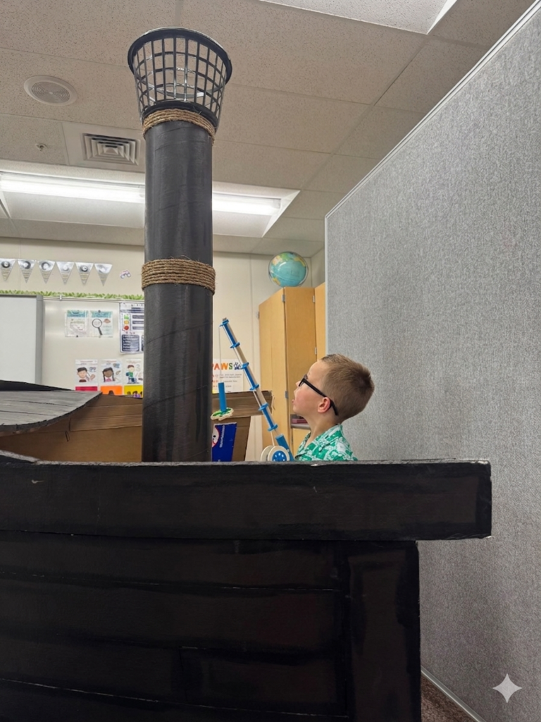 students smiling and fishing in a card board pirate ship